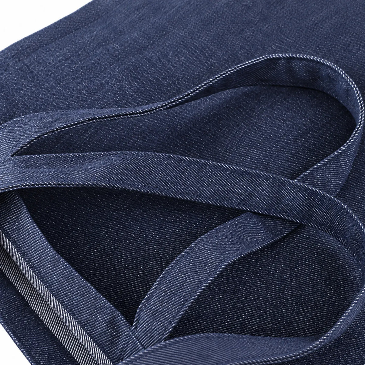 Close-up of an indigo blue fabric item with woven straps and visible stitching details.