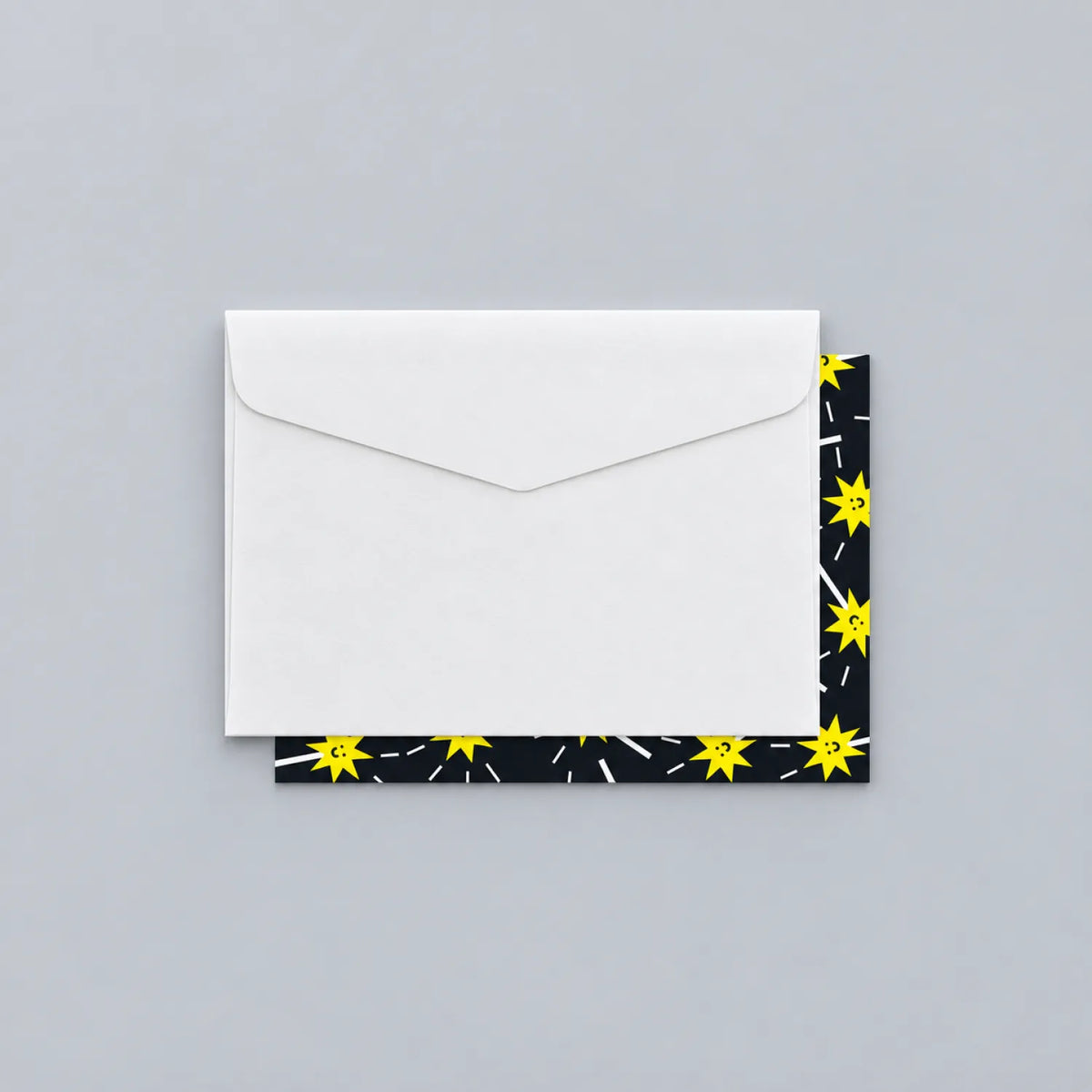 White envelope resting on an illustrated greeting card with a black and yellow star pattern