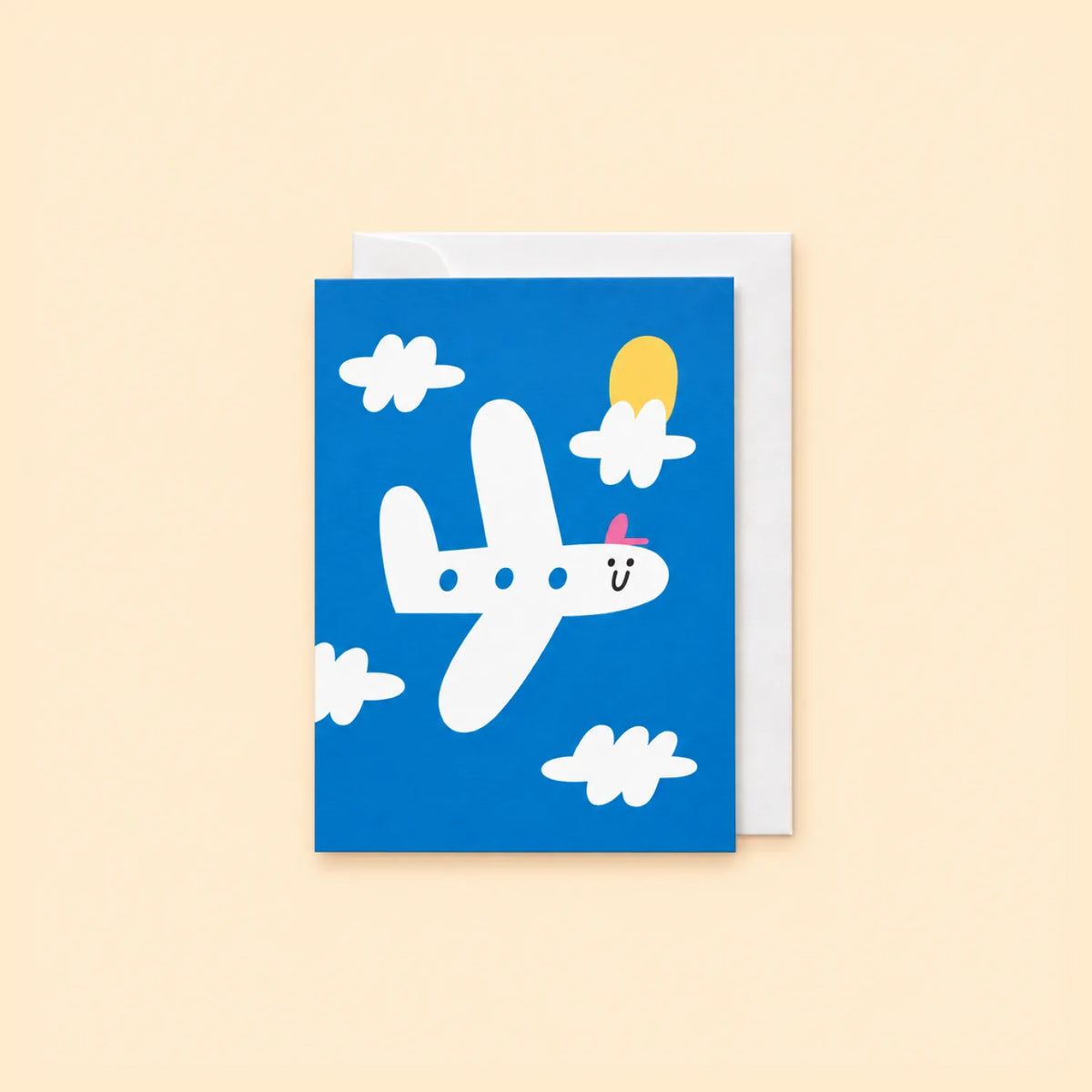 Blue New Journey greeting card with a smiling white plane, clouds and yellow sun, shown with white envelope