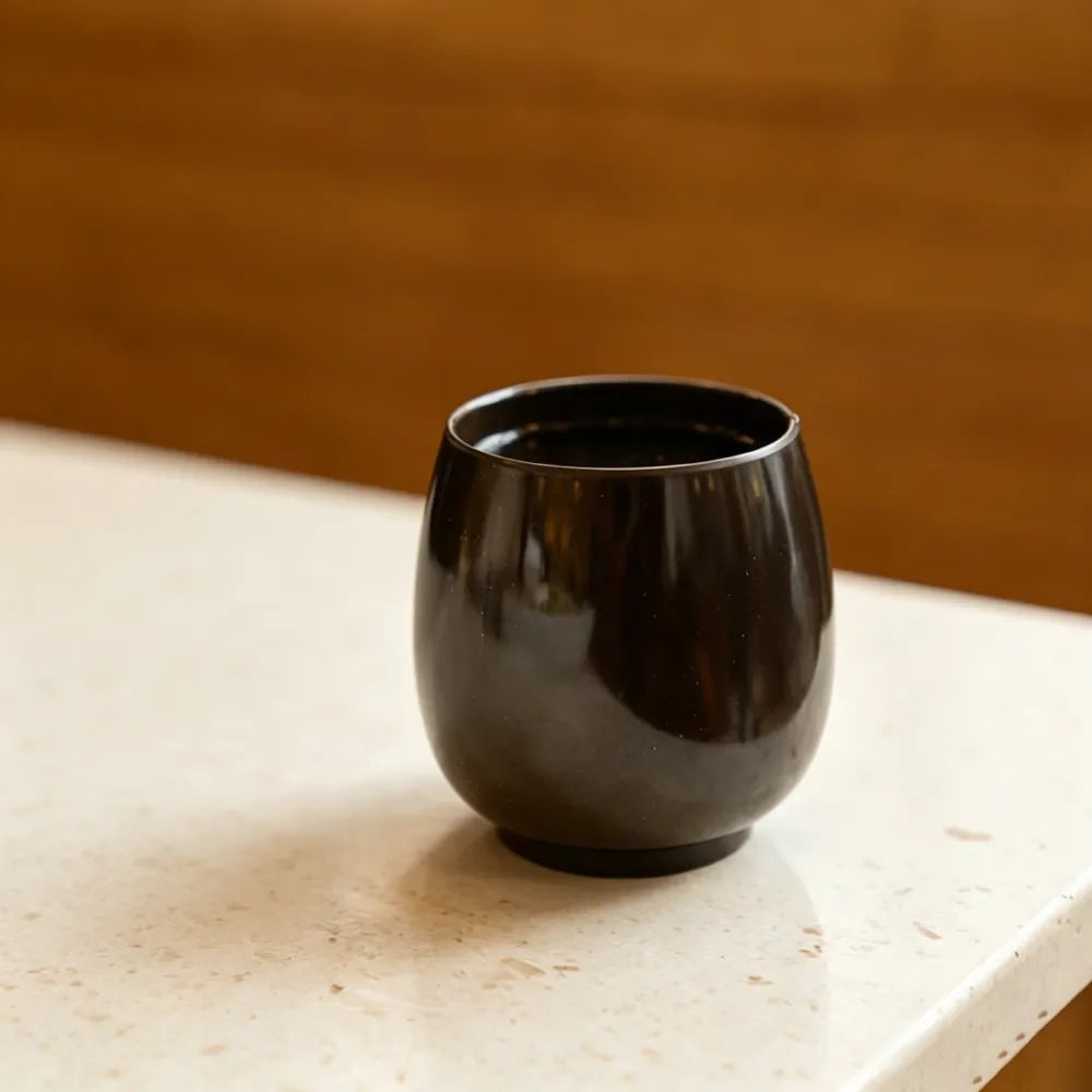 Dark brown aroma recycled coffee grounds coffee cup on a stone benchtop against a warm timber background, lifestyle setting, no branding applied