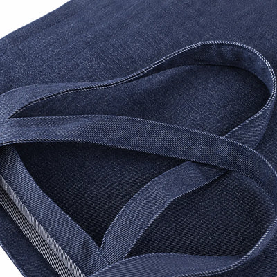 Close-up of an indigo blue fabric item with woven straps and visible stitching details.