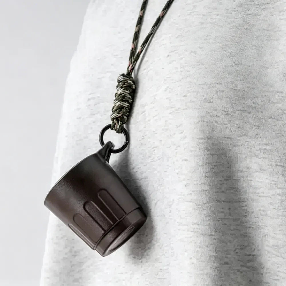 Dark brown Doric recycled coffee grounds tasting cup worn on a braided olive lanyard over a grey marl top, vertical ribbed profile visible, no branding applied