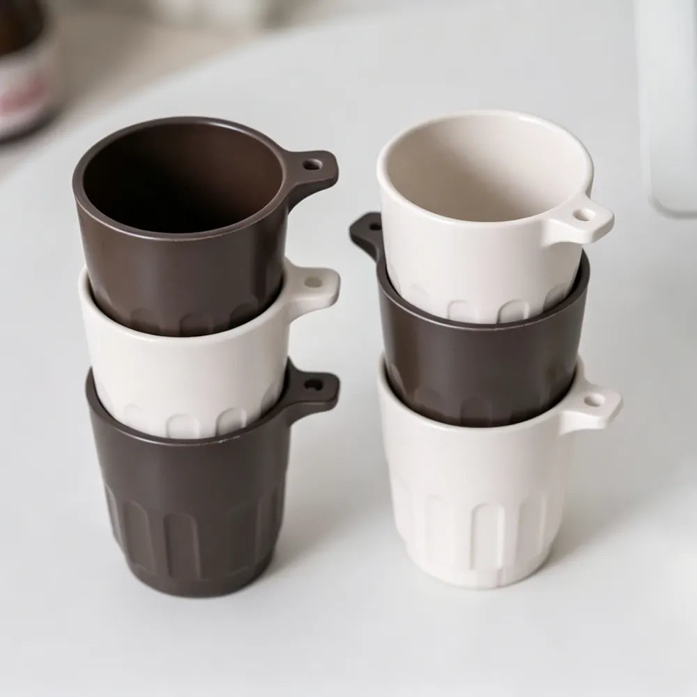 Six Doric recycled coffee grounds tasting cups stacked in two columns, alternating dark brown and off-white colourways, showing the stackable design, no branding applied