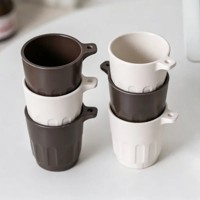 Six Doric recycled coffee grounds tasting cups stacked in two columns, alternating dark brown and off-white colourways, showing the stackable design, no branding applied