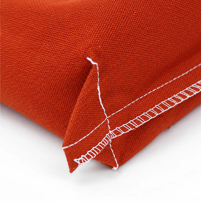 Close-up of a textured clay-orange woven canvas corner with white contrast stitching on a white background.
