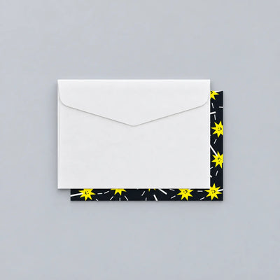 White envelope resting on an illustrated greeting card with a black and yellow star pattern