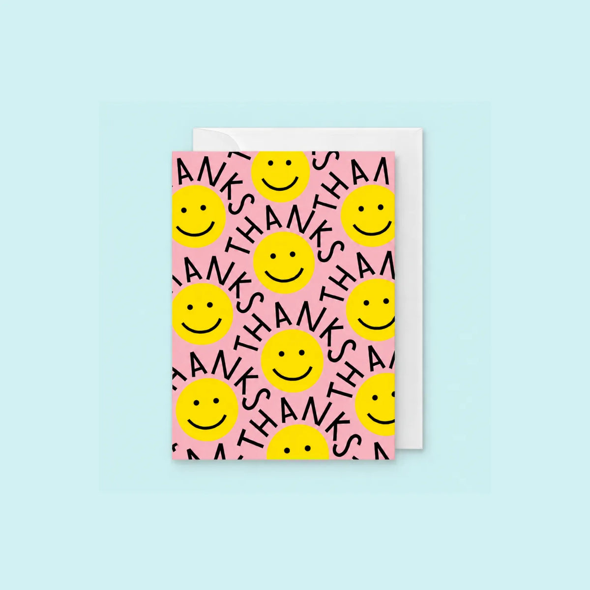 Pink Thanks greeting card with yellow smiley faces and repeated Thanks lettering, shown with white envelope