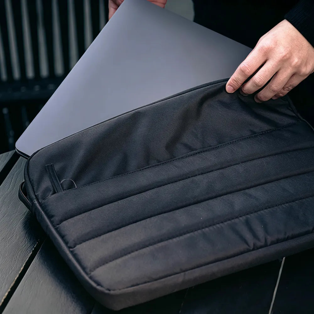 Laptop being inserted into custom branded Repreve recycled laptop sleeve, employee welcome kit merch by Wumble Merch Australia