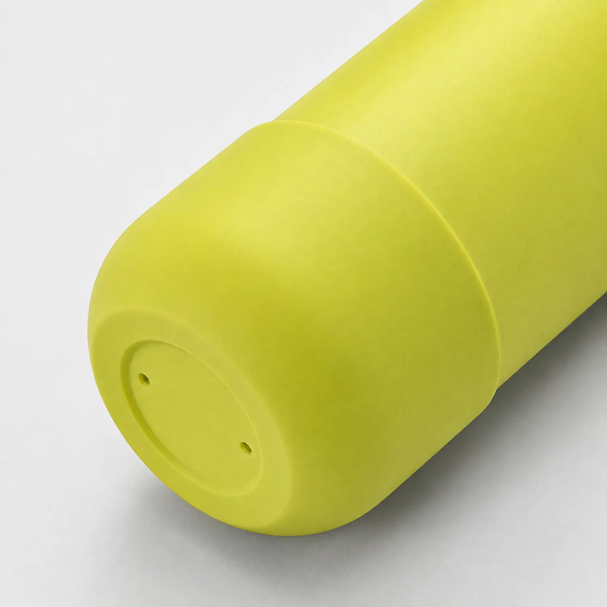 Close view of a yellow-green drink bottle base with a rounded edge and a matte finish.