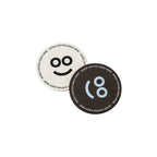 Off-white and dark brown round recycled coffee grounds coasters printed with a sample smiley face and "good coffee goes here" border, white background, branded example