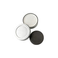 Open round metal tin holding off-white recycled coffee grounds coasters beside its lid, showing the gift tin packaging, no branding applied