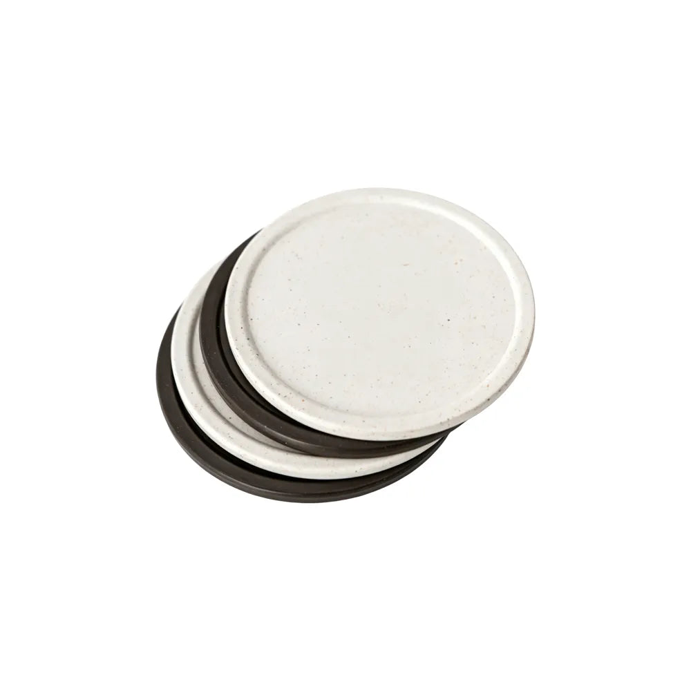 A stack of round recycled coffee grounds coasters in off-white and dark brown on a white background, off-white coaster on top showing the speckled texture, no branding applied