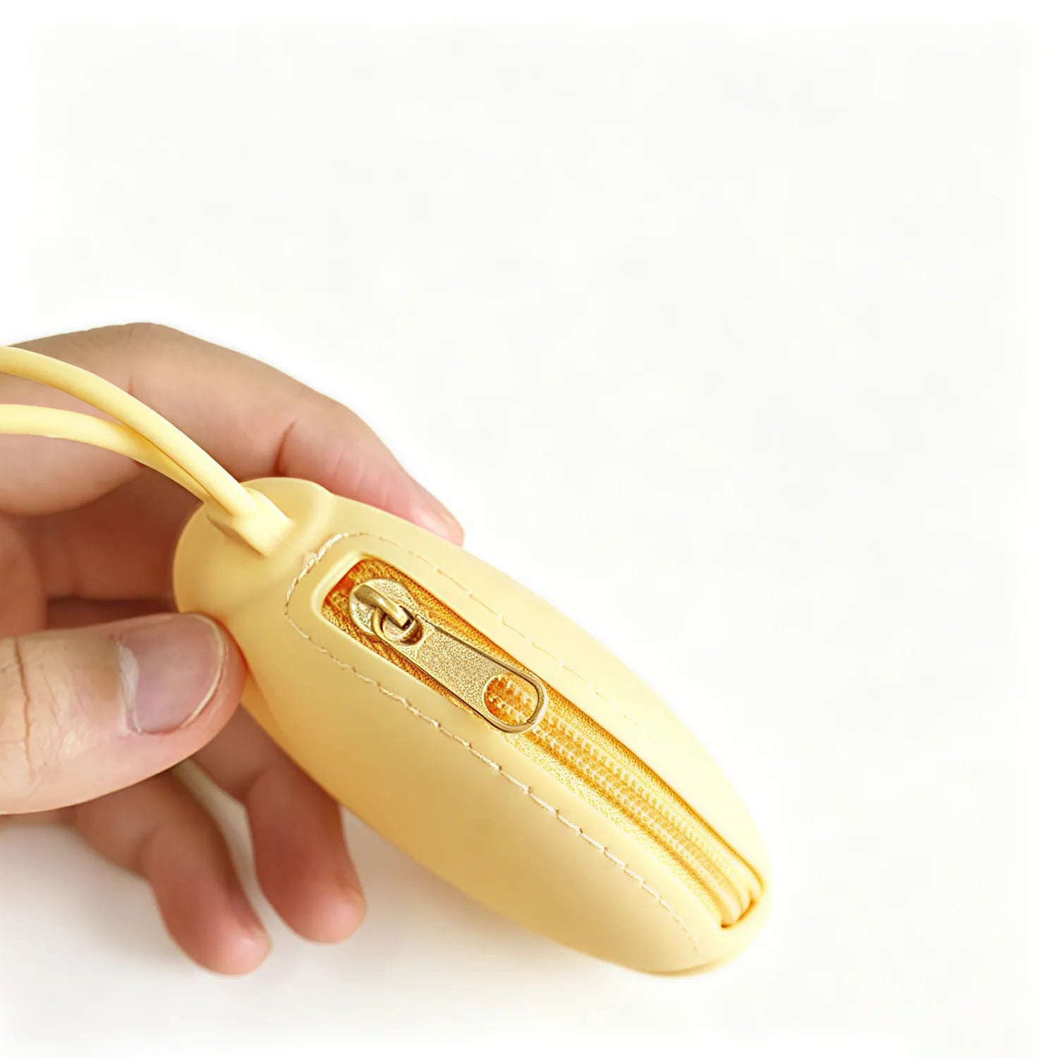 Close view of the metal zip and pull on a butter yellow round silicone zip pouch held in hand, no Wumble branding applied