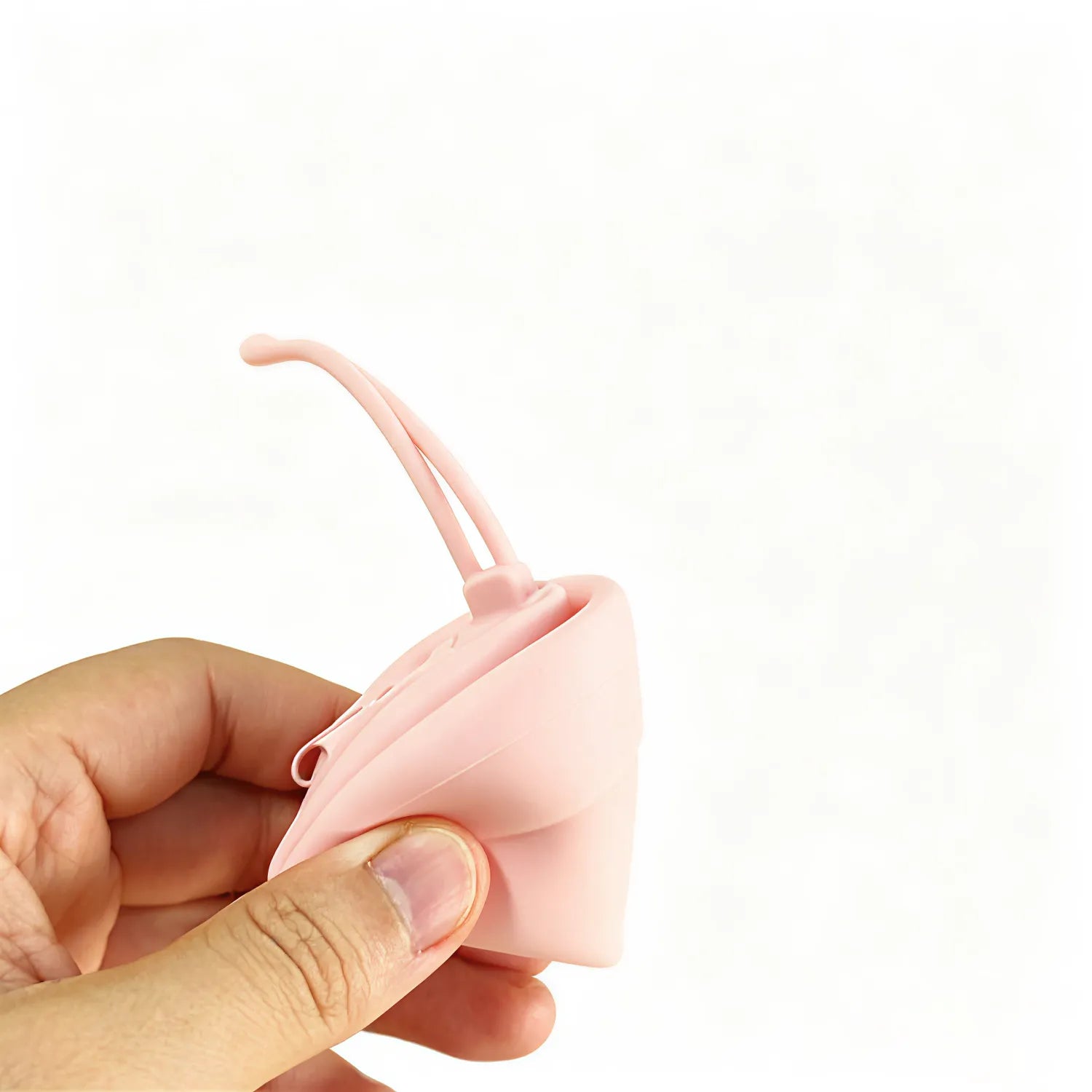 Pink round silicone zip pouch squeezed open in hand to show the soft flexible silicone, no Wumble branding applied