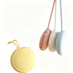 Butter, white and icy blue round silicone zip pouches hanging by their loops beside a butter pouch resting flat, showing the colour range, no Wumble branding applied
