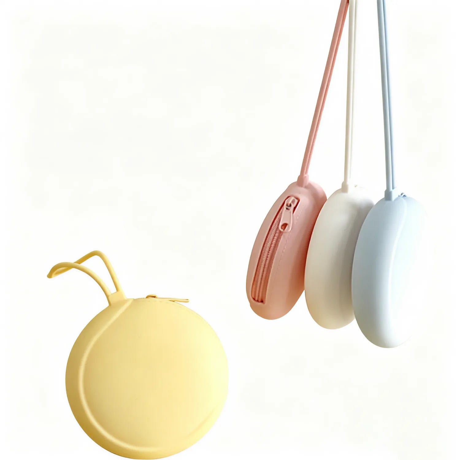 Butter, white and icy blue round silicone zip pouches hanging by their loops beside a butter pouch resting flat, showing the colour range, no Wumble branding applied