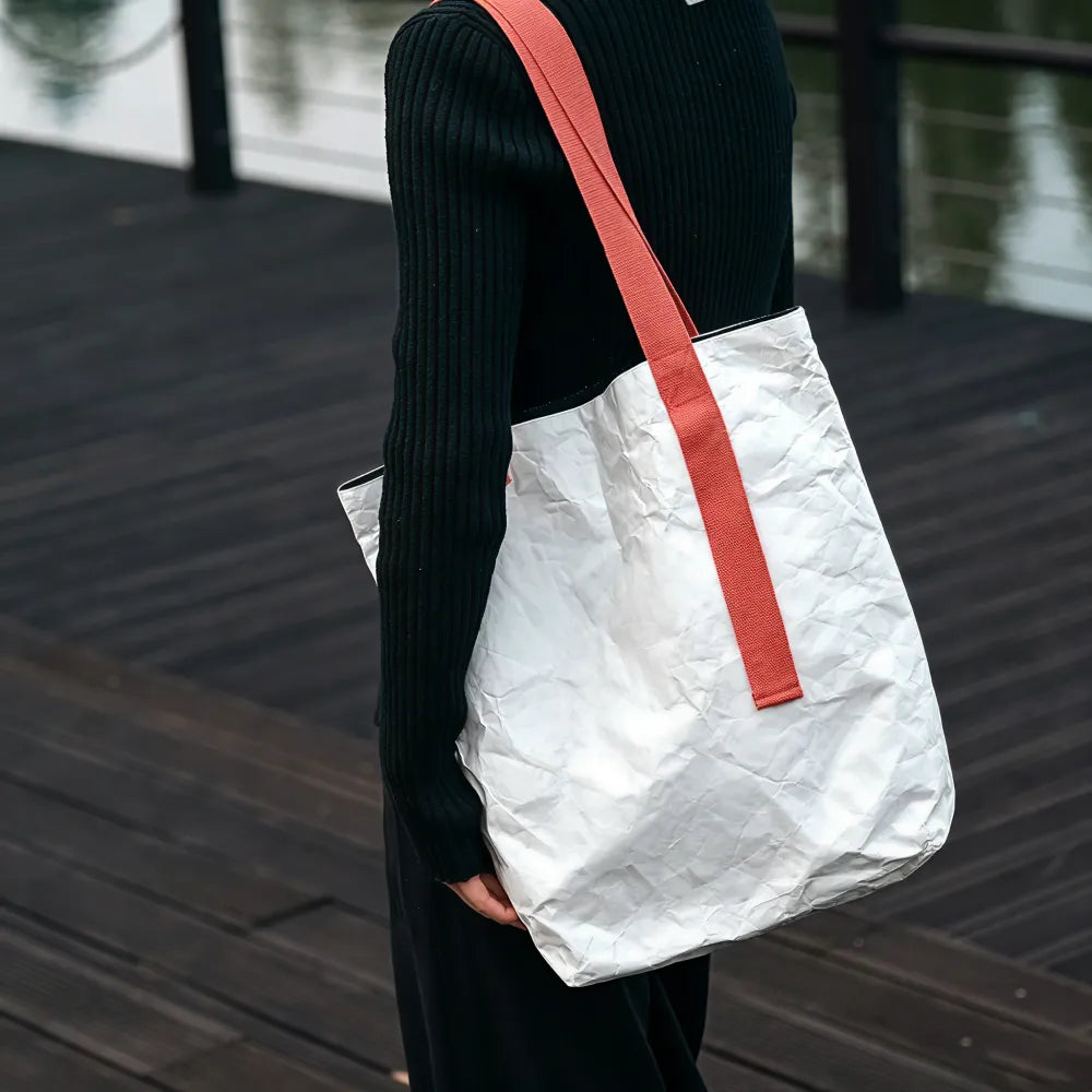 Person carrying custom branded Tyvek paper tote bag, sustainable event merch by Wumble Merch Australia