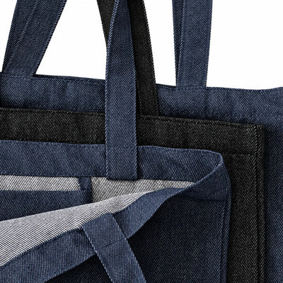 Close-up of denim tote bags with handles and a striped interior lining in black and indigo blue, shown against a white background.