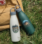 Cream white and deep forest green 750ml PLA bottle-style travel cup with a grey loop-top lid on a outdoor grass, branding applied